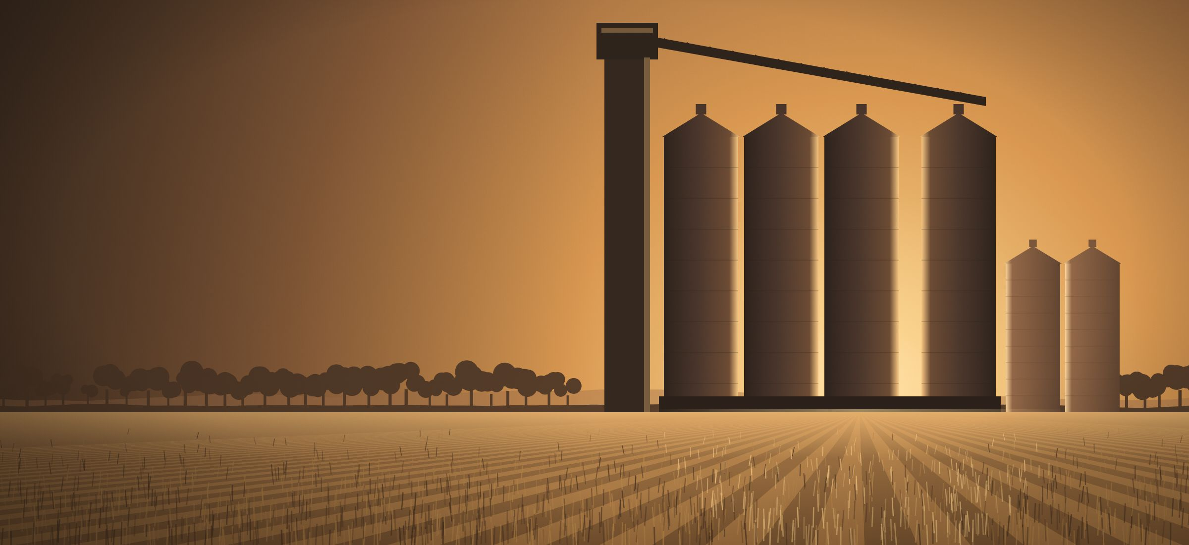 Grain silos silhouetted against a golden evening sky above harvested fields